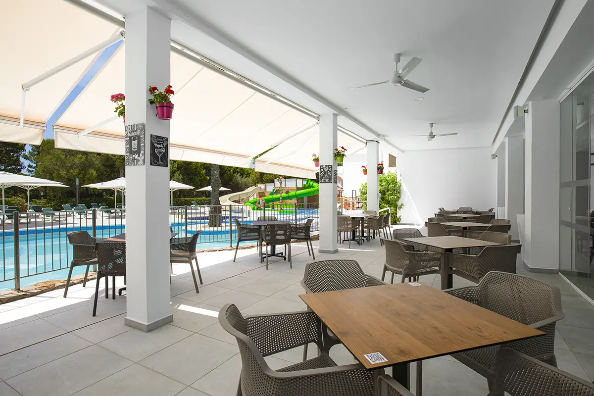 Terraza cubierta con mesas y sillas en Hotel Cala d’Or Playa