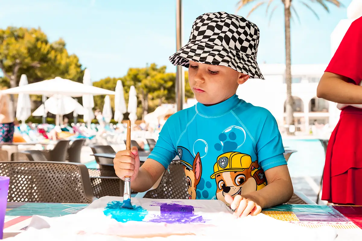 Niño pintando una camiseta a mano en Hotel Cala d’Or Playa