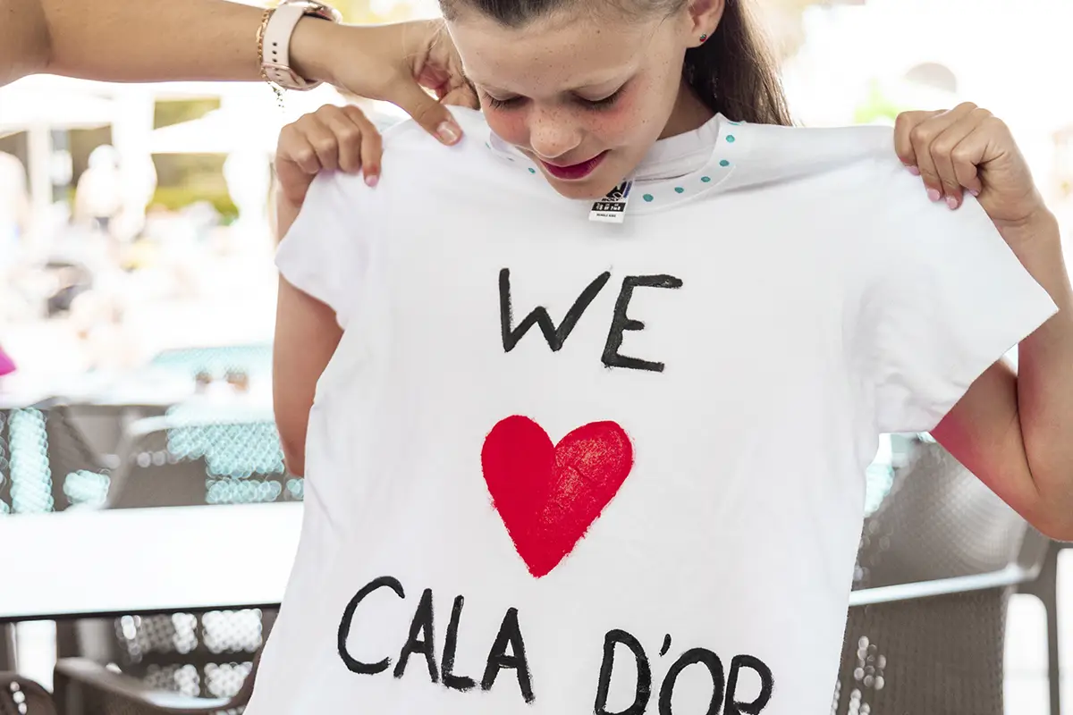 Niña probándose una camiseta pintada a mano en Hotel Cala d’Or Playa